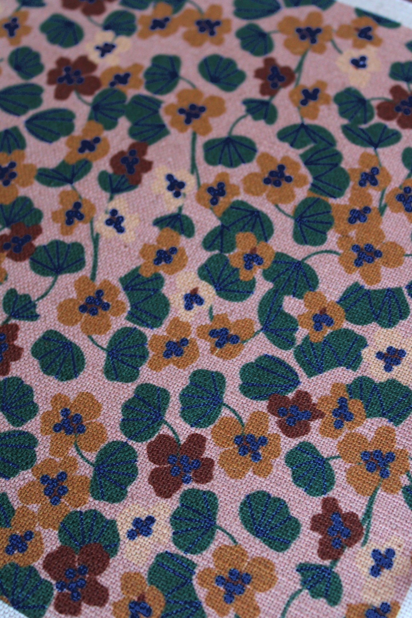 Floral patterned fabric with green, brown, and blue flowers on a pink background
