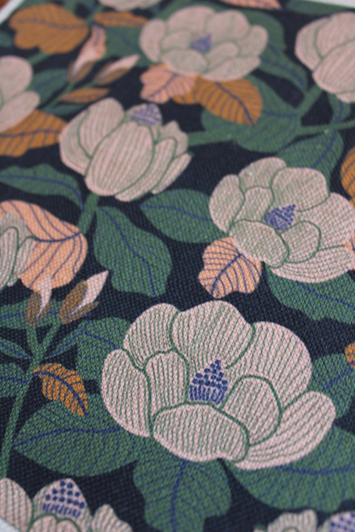 Close-up of floral patterned fabric with green, pink, and orange colors on a dark background.