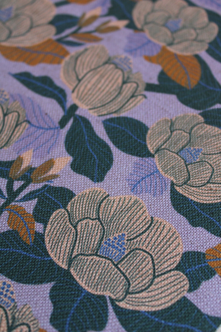 Close-up of floral fabric pattern with green and brown flowers on a light blue background