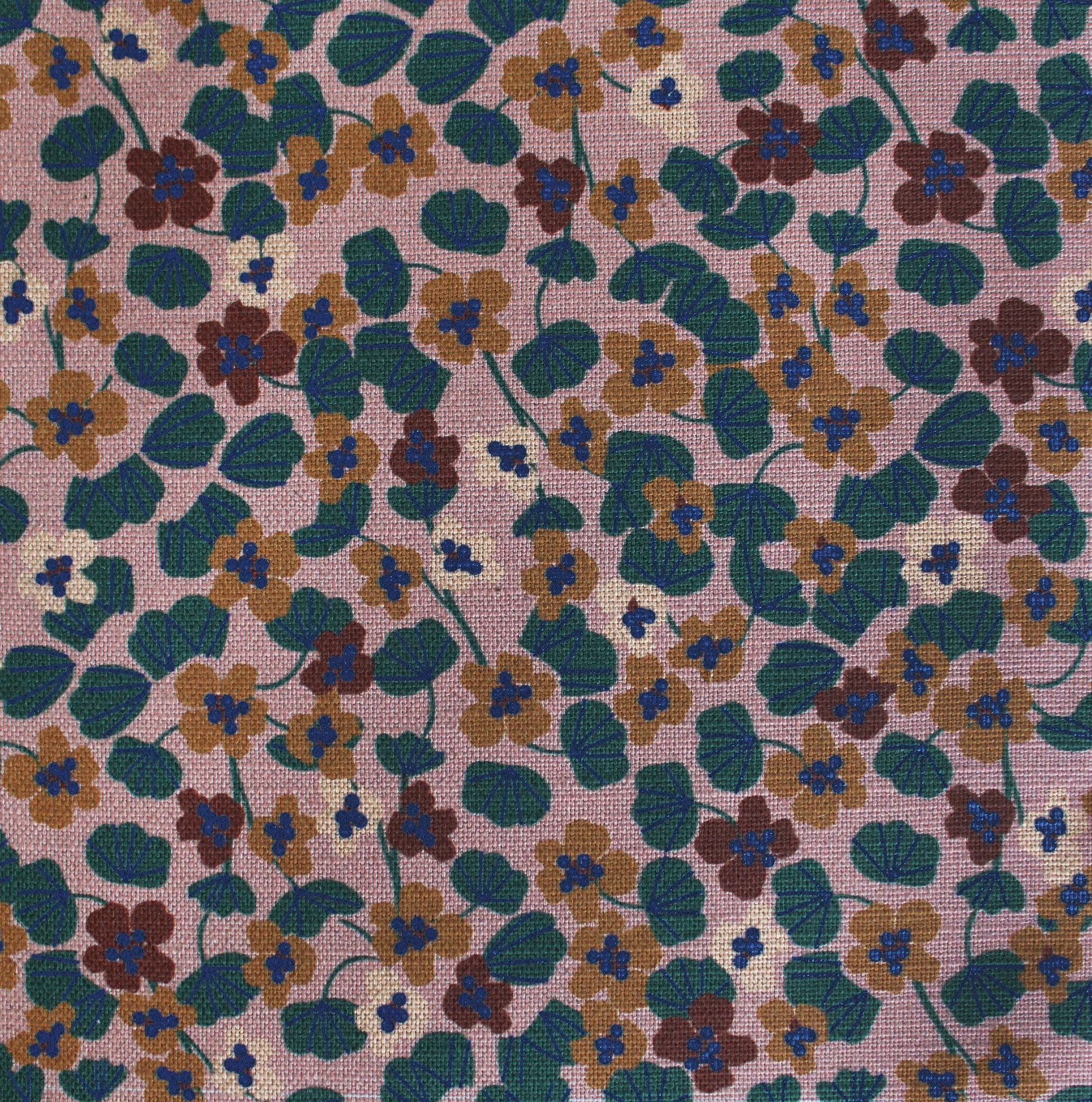 Floral patterned fabric with small flowers in green, brown, and blue on a pink background