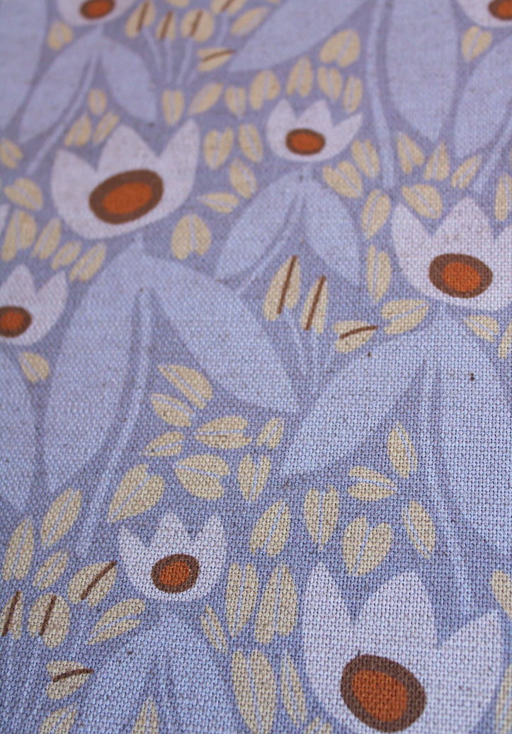 Close-up of floral fabric pattern with white flowers and brown centers on a blue background