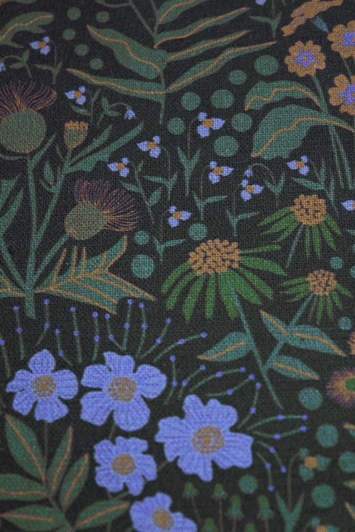 Patterned fabric with blue flowers and green leaves on a black background